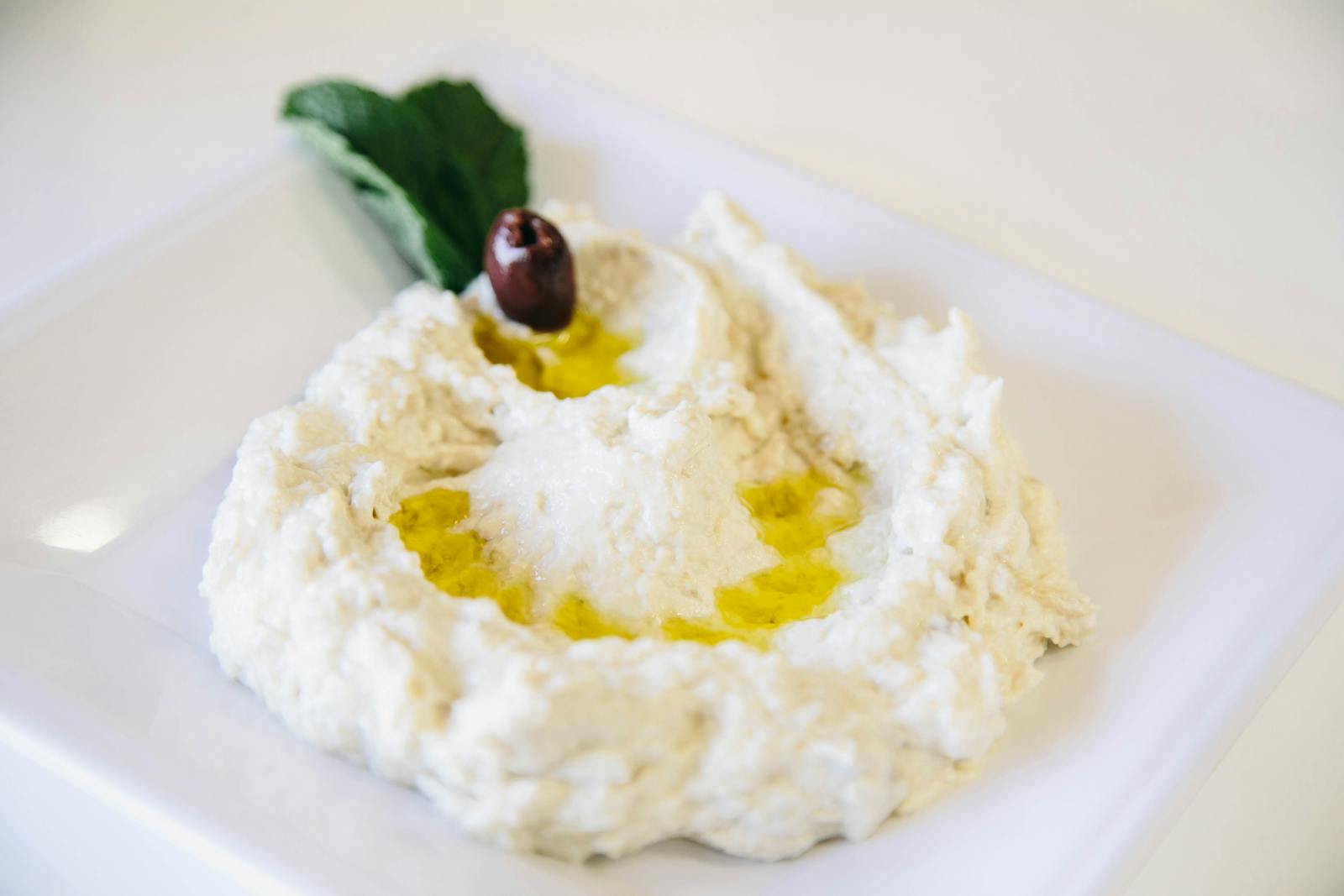 Creamy Mediterranean side topped with olive oil and an olive